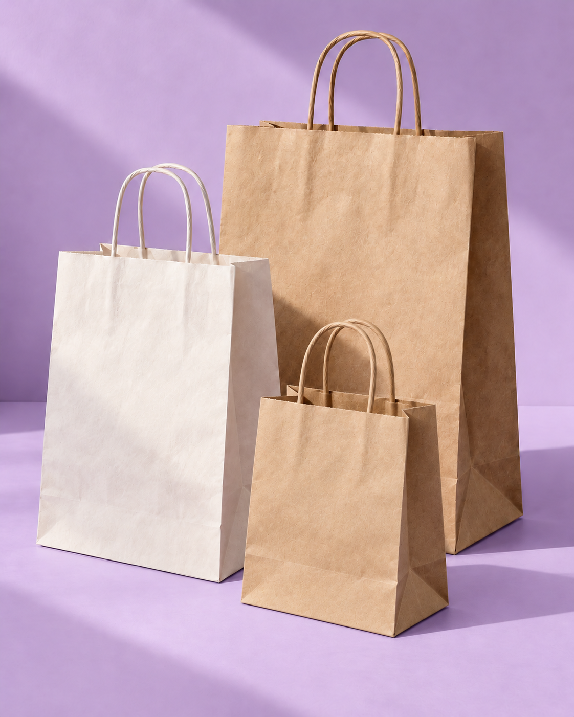 Tres bolsas de papel, una blanca y dos kraft, de diferentes tamaños